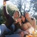 Happy family taking a selfie during a sunny picnic in a park.